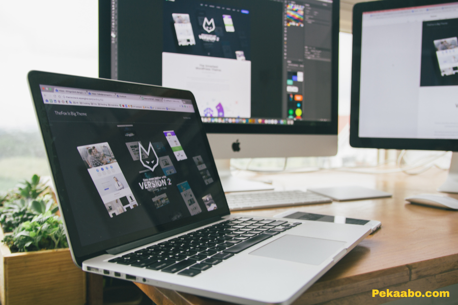 Laptop displaying a website design project on an office desk with monitors for Pekaabo web development services